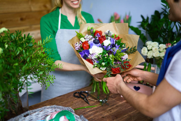 Πωλητής δίνοντας λουλούδια διατεταγμένα ανθοδέσμη στον αγοραστή - Φωτογραφία, εικόνα