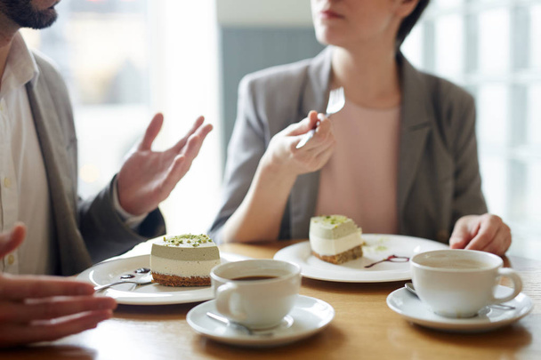 Два человека едят вкусный десерт и разговаривают в кафе
 - Фото, изображение