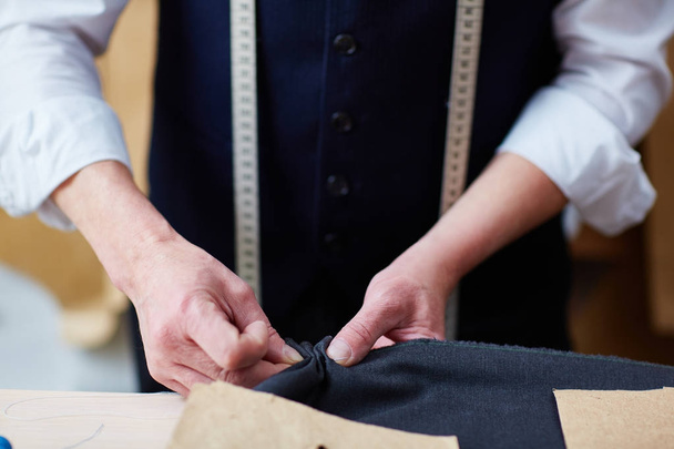 Gros plan d'un tailleur qualifié travaillant en atelier : épinglage et couture de tissu lors de la couture de vêtements
 - Photo, image