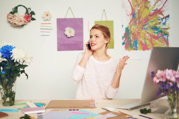 Poważne projektant graficzny, prowadząc rozmowy telefonicznej trudne z jej klienta i gestykulując w tym samym czasie w studio kolorowe - Zdjęcie, obraz