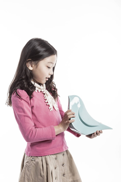 ein Mädchen hält einen Keramikvogel in der Hand. (trägt eine rosa Bluse) - Foto, Bild