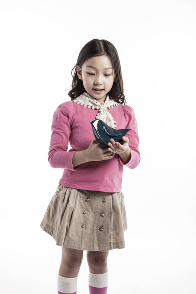 ein Mädchen hält einen Keramikvogel in der Hand. (trägt eine rosa Bluse)  - Foto, Bild