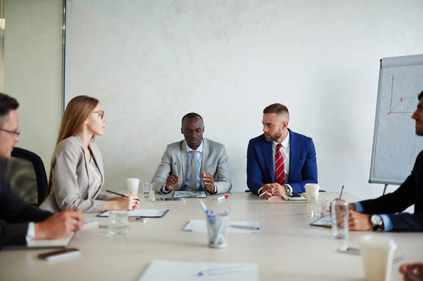 Коллеги на рабочем совещании: они собрались за столом и внимательно слушали своего афро-американского босса
 - Фото, изображение