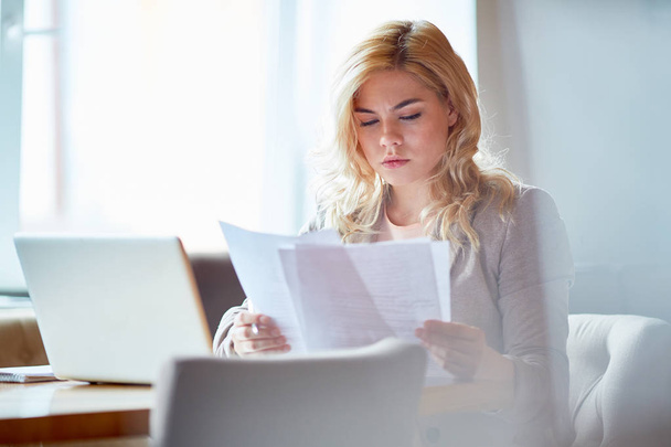 Confident accountant reading financial papers by her workplace - Photo, image