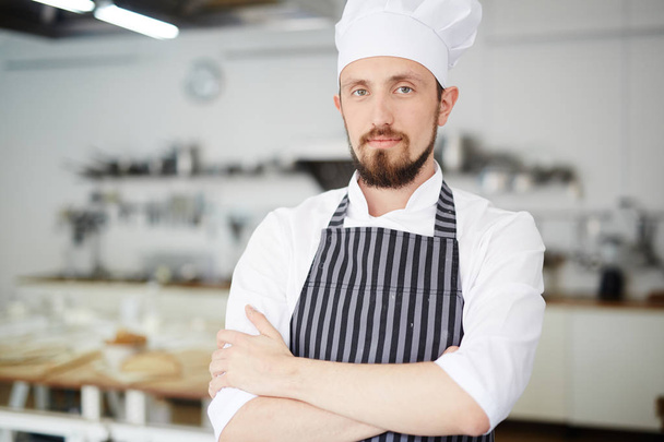 Bearded baker in uniform looking at camera - Fotó, kép