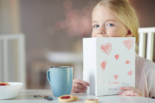 Cute girl peeking out of greeting card for her mother - Photo, Image
