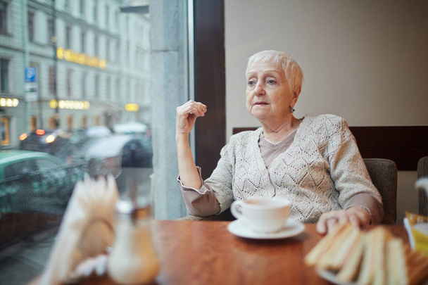 Συνταξιούχος γυναίκα έχοντας υπόλοιπο σε μία από τις καφετέριες της πόλης - Φωτογραφία, εικόνα