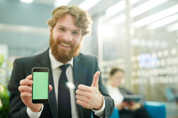 Szczęśliwy człowiek pokazuje kciuk up podczas pokazywania nowych aplikacji w smartfonie - Zdjęcie, obraz