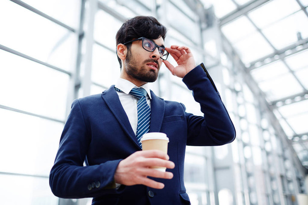 Posh young man in suit and eyeglasses holding drink - Foto, Imagen