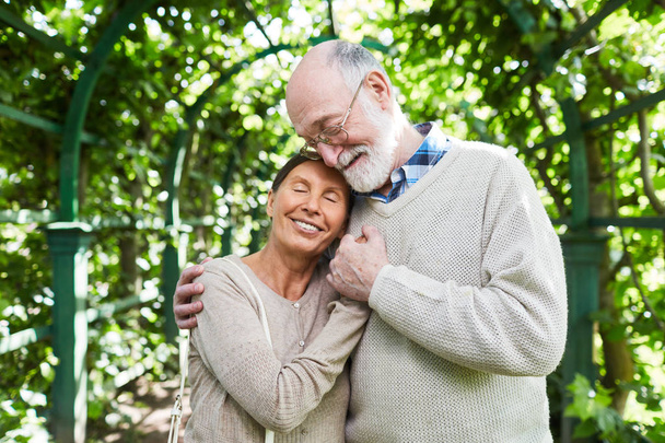 Amorous kypsä pari seisoo syleilyssä sisällä puu-kuja kesäpäivänä
 - Valokuva, kuva