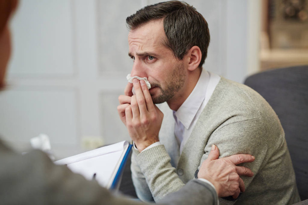 Hombre adicto al alcohol limpiando lágrimas durante la conversación con el psicólogo
 - Foto, Imagen