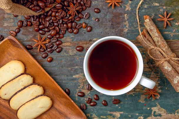 warme Kaffeetasse mit gerösteten Bohnen auf rustikalem Tisch - Foto, Bild