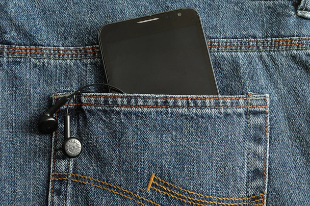 İnce bir telefon ve kulaklık arka cebinde bir Jean - Fotoğraf, Görsel