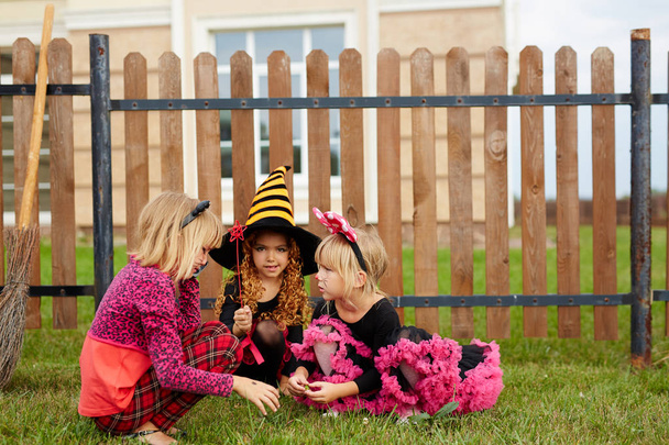 Trzy dziewczyny w tradycyjne stroje halloween gra na podwórku przez płot - Zdjęcie, obraz