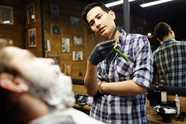 Maestro di rasatura in camicia e guanti consulenza uno dei clienti nel proprio barbiere
 - Foto, immagini