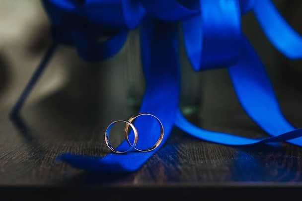 Золотые свадебные кольца лежат на деревянном столе
 - Фото, изображение