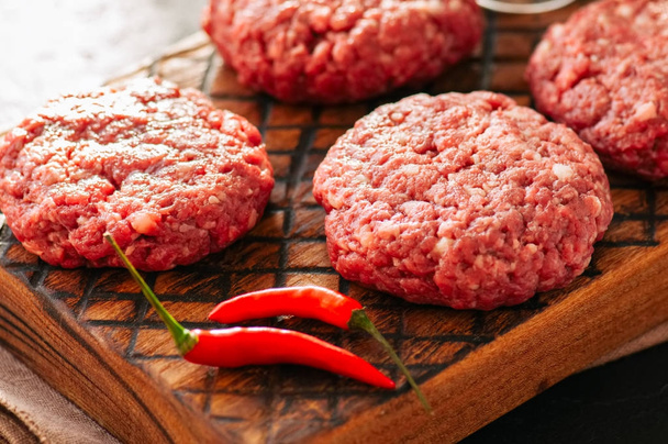Close up of raw ground meat beef burgers on a wooden board.  - Фото, зображення