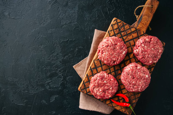 Hamburgery z wołowiny ziemi surowego mięsa na płycie.  - Zdjęcie, obraz