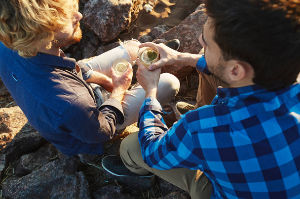 Blick aus der Vogelperspektive auf bärtige junge Freunde, die Hemden tragen und Mojito-Cocktails trinken, während sie sich im Freien versammeln - Foto, Bild