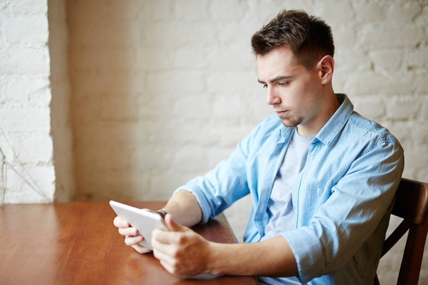 Boční pohled portrét moderní mladý muž pomocí přenosné digitální tabletu a při pohledu na obrazovku - Fotografie, Obrázek