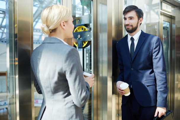 Portrait of two business colleagues, man and woman, chatting in elevator of modern office building - Foto, Imagem