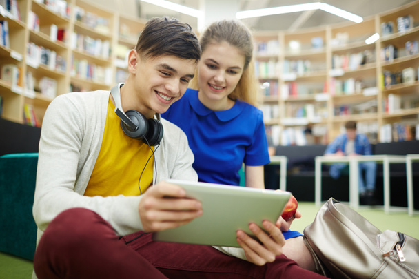 Öğrenciler çift, gülümseyen ve dijital tablet ekranına kolej kütüphane salonunda bakarak kullanan kız, portre - Fotoğraf, Görsel