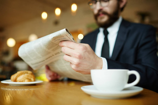 Newspaper in hands of jobless man having coffee in cafe - Foto, afbeelding