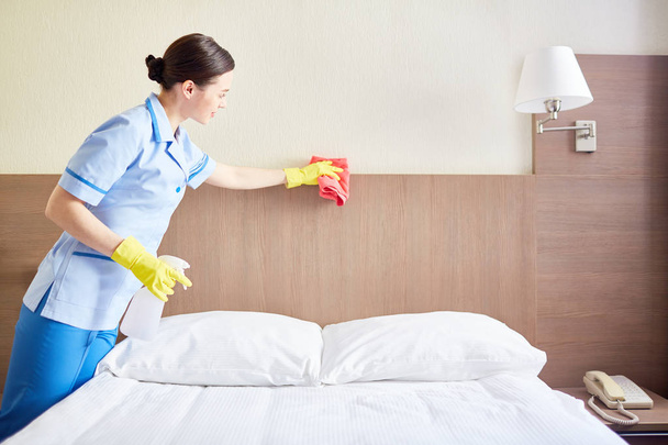 Szép, takarítás ágy, szállodai szobában szivaccsal szobalány - Fotó, kép