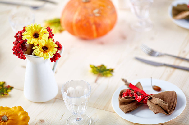Цветы и ягоды в вазе на деревянном сервированном праздничном столе
 - Фото, изображение