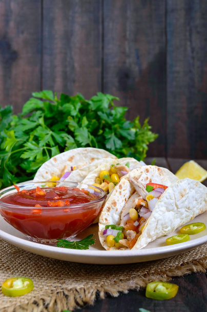 Taco - buğday tortilla et, sebze, yeşillik ve domates ile Mısır ile koyu ahşap arka plan üzerinde sos. Geleneksel Meksika mutfağı. - Fotoğraf, Görsel
