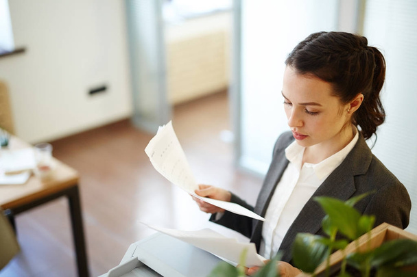Молодой менеджер читает деловые документы или контракты в офисе
 - Фото, изображение