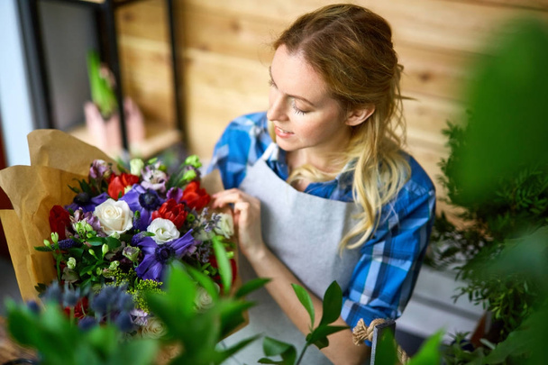 Owner of flower-shop looking at bouquet - Photo, Image