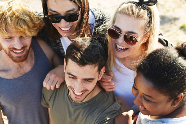 Vista de ángulo alto de grupo multiétnico de amigos con amplias sonrisas reunidos al aire libre y divertirse
 - Foto, Imagen