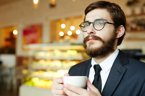 Handsome gentleman with cup of tea sitting in cafe after or before working day - 写真・画像