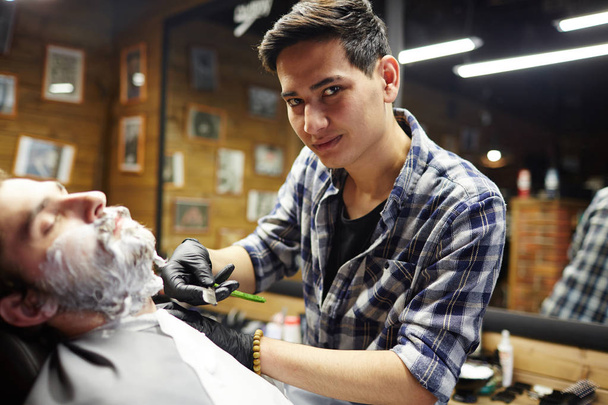 Master of shaving doing his work in barbershop - Photo, Image