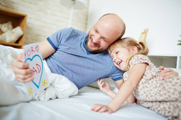 Szczęśliwy człowiek, czytanie życzenia na dzień ojca z córeczką w pobliżu przez - Zdjęcie, obraz