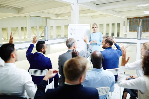 Participantes de seminários de negócios levantando as mãos para responder pergunta treinador após a apresentação
 - Foto, Imagem