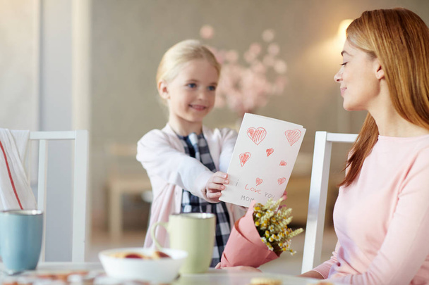 hübsche junge Frau schenkt ihrer Mutter handgemachte Grußkarte - Foto, Bild