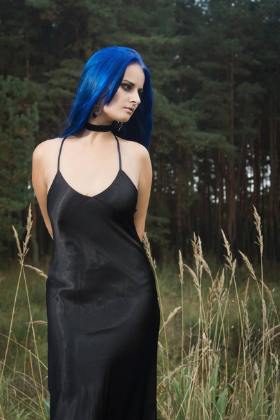 Mooie vrouw met donker blauwe haar gekleed in zwarte jurk in th - Foto, afbeelding