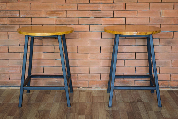 duas cadeiras de madeira no fundo da parede de tijolo
 - Foto, Imagem