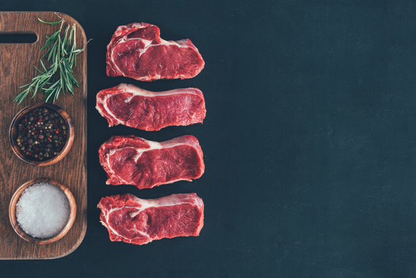 satırda baharatlar ile çiğ biftek üstten görünüm ahşap tahta üzerinde - Fotoğraf, Görsel