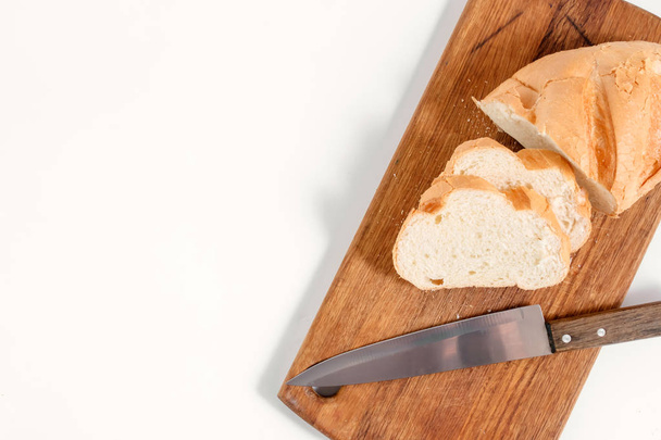 White bread lies on a kitchen board with a knife view from above on a white background - Фото, зображення