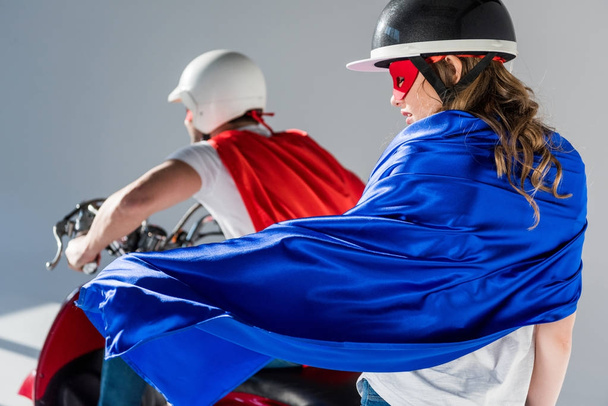 selectieve aandacht van paar in helmen en superheld capes op scooter - Foto, afbeelding