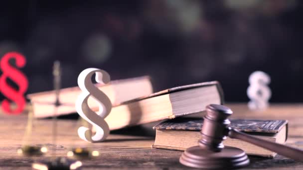 Jogi és igazságszolgáltatási koncepció. Törvény szimbólumok a fából készült asztal és bokeh háttérben. Dolly-lövés. - Felvétel, videó
