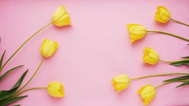 Kompozycja kwiat z żółtych tulipanów, po bokach na różowym tle - Zdjęcie, obraz
