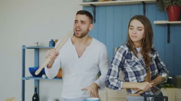Happy joyful couple have fun dancing and singing while cooking in the kitchen at home on vacation - Záběry, video