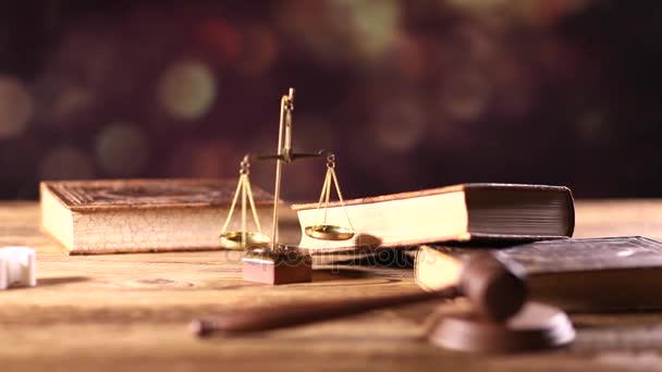 Jogi és igazságszolgáltatási koncepció. Törvény szimbólumok a fából készült asztal és bokeh háttérben. Dolly-lövés. - Felvétel, videó
