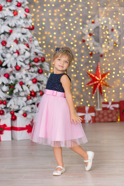 Christmas Happy funny children child girl enjoying new year decoration studio with presents tree mirror and sofa chair dressed in casual airy dresses - Foto, afbeelding
