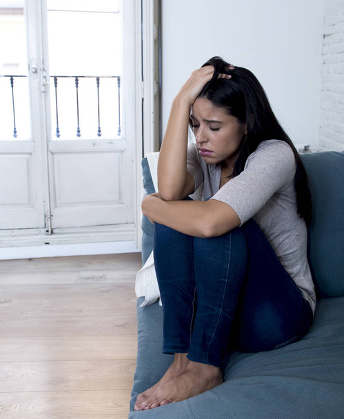 mladá atraktivní žena Latinské ležící doma na gauči v obývacím pokoji unavený a strach, utrpení deprese pocit, smutný a zoufalý s bolestí hlavy - Fotografie, Obrázek
