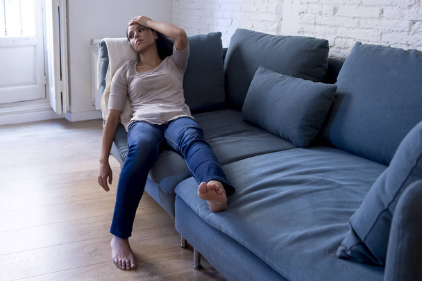 ελκυστική Λατινική γυναίκα ξαπλωμένη στο σπίτι καναπέ του σαλονιού κουρασμένος και ανησυχούν πάσχει κατάθλιψη συναίσθημα θλιβερό και απεγνωσμένα με πονοκέφαλο - Φωτογραφία, εικόνα